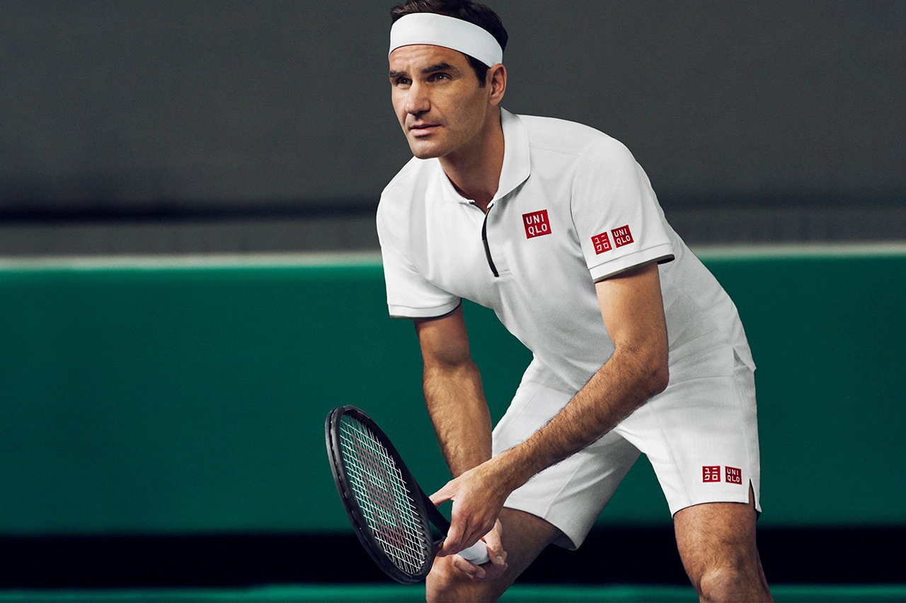 Roger prepares to return serve, wearing a white tennis uniform emblazoned with Uniqlo's classic red logo